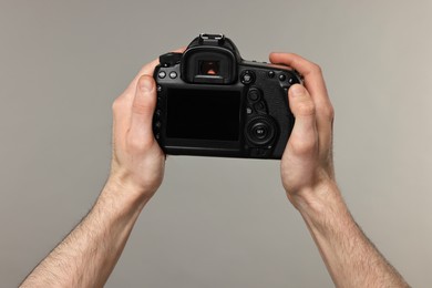 Photo of Photographer holding camera on grey background, closeup