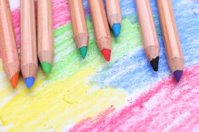 Photo of Colorful pastel pencils on abstract drawing, closeup