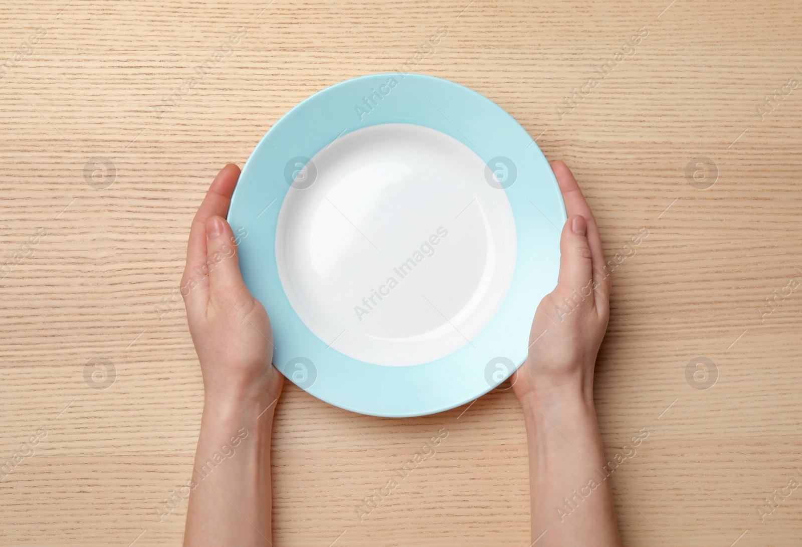 Photo of Woman with empty plate at wooden table, top view