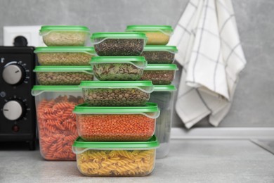 Photo of Plastic containers filled with food products on grey table in kitchen. Space for text