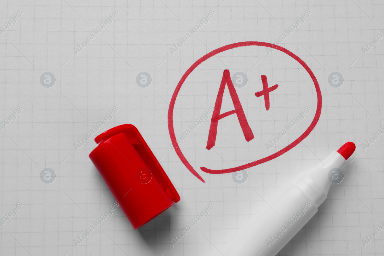 Photo of School grade. Red letter A with plus symbol on notebook paper and marker, top view