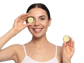 Photo of Beautiful young woman putting slices of cucumber on eyes against white background