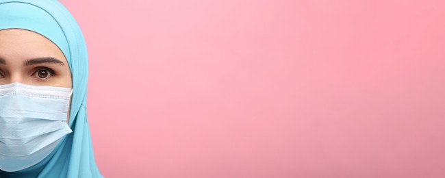 Image of Portrait of Muslim woman in hijab and medical mask on pink background, space for text. Banner design