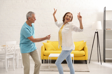 Photo of Happy senior couple dancing in kitchen at home