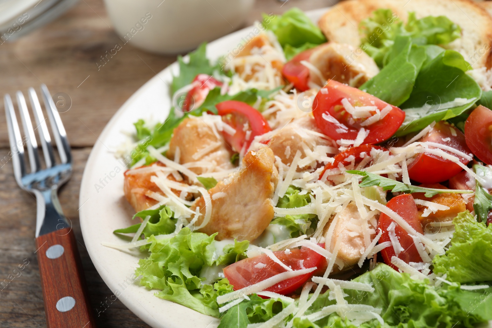 Photo of Delicious fresh Caesar salad on wooden table, closeup