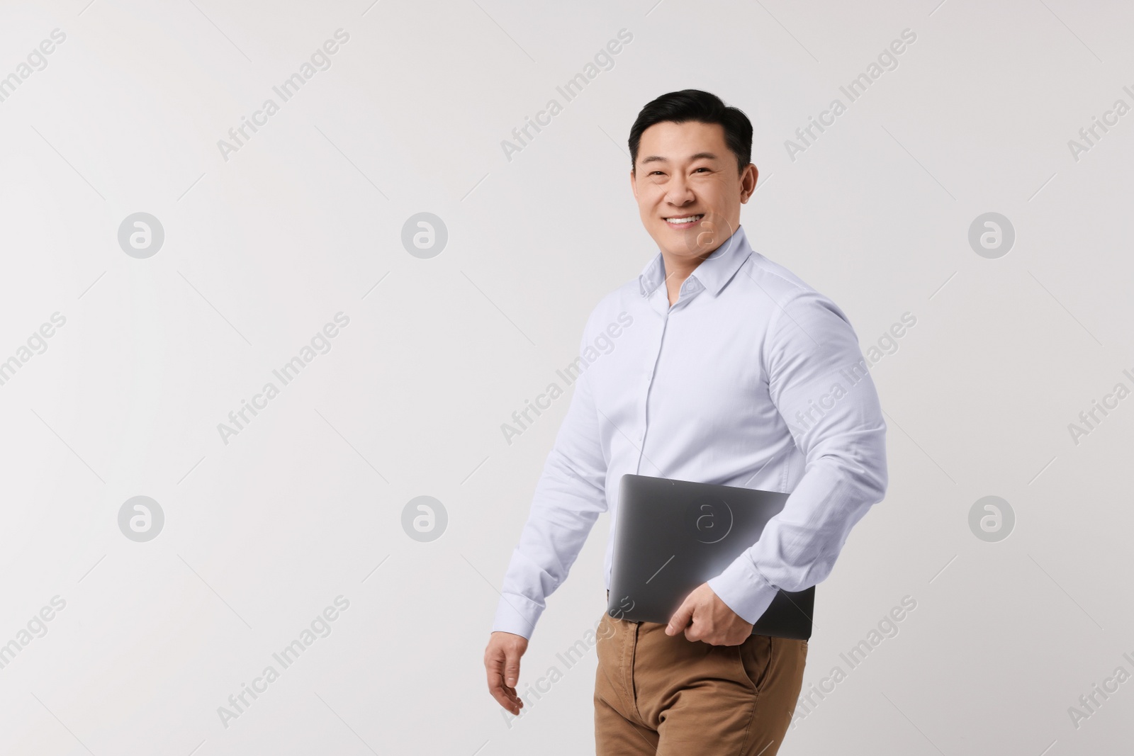 Photo of Portrait of happy man with laptop on light background. Space for text