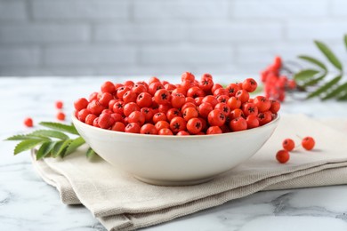 Photo of Fresh ripe rowan berries in bowl on white marble table