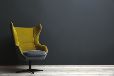 Photo of Comfortable office chair near black wall indoors. Space for text