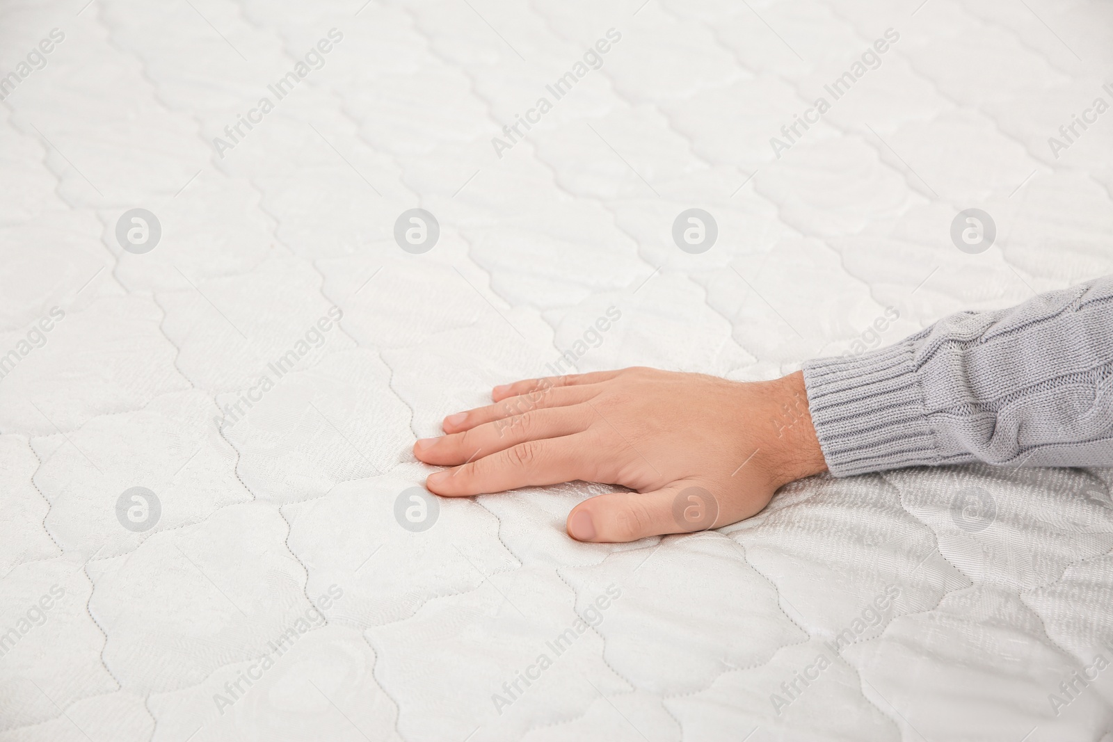 Photo of Man checking firmness of mattress, closeup view