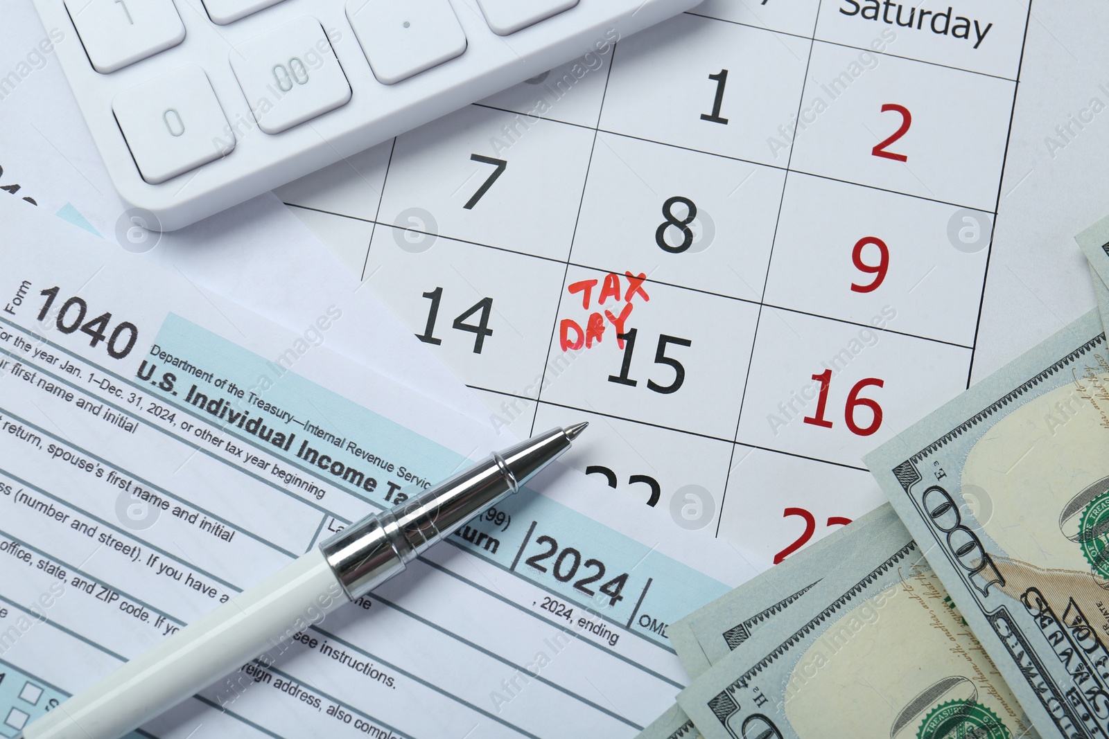 Photo of Calendar with date reminder about tax day, documents, pen, calculator and money, top view