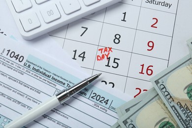 Calendar with date reminder about tax day, documents, pen, calculator and money, top view