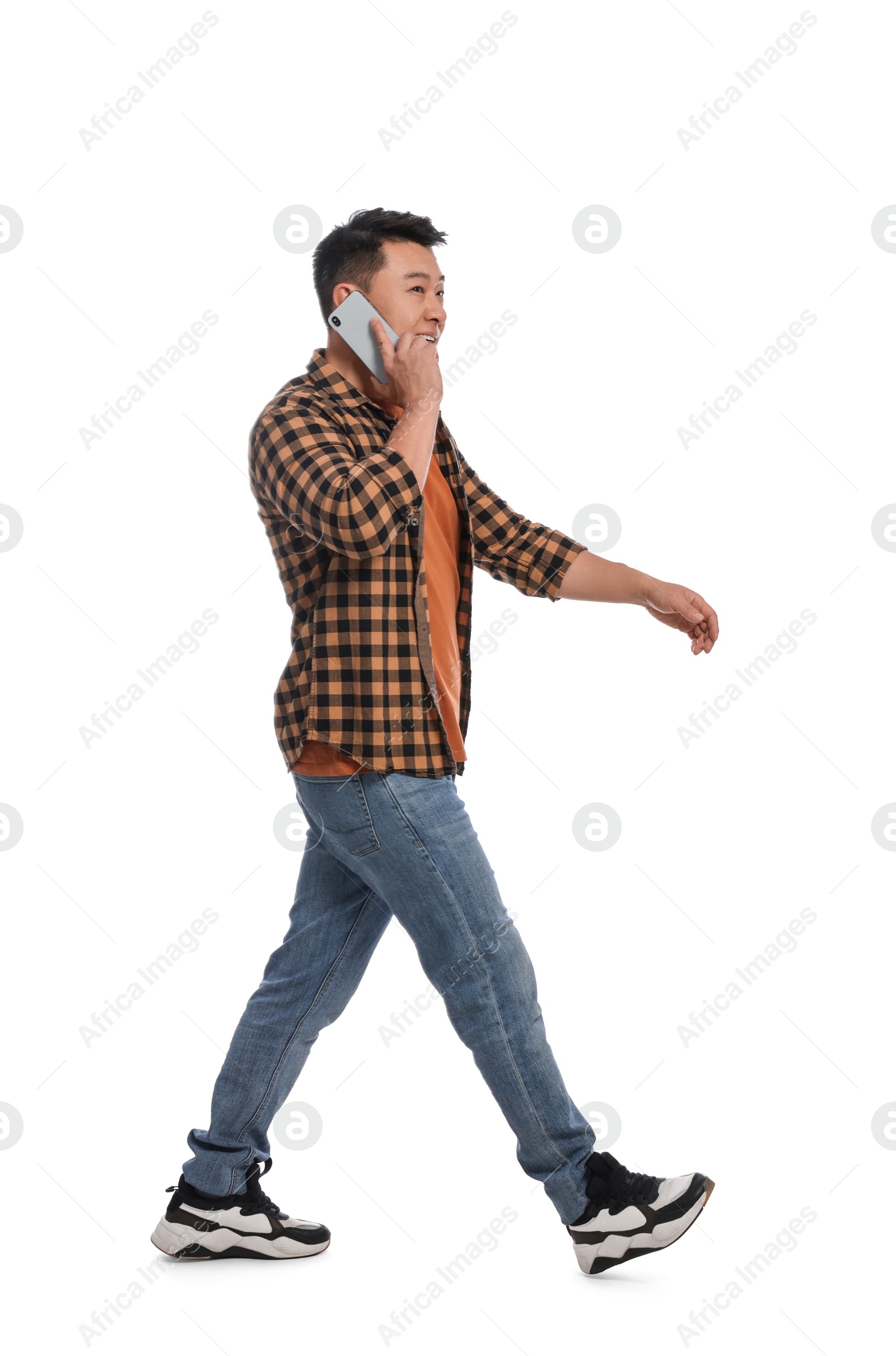 Photo of Man talking on smartphone while walking against white background