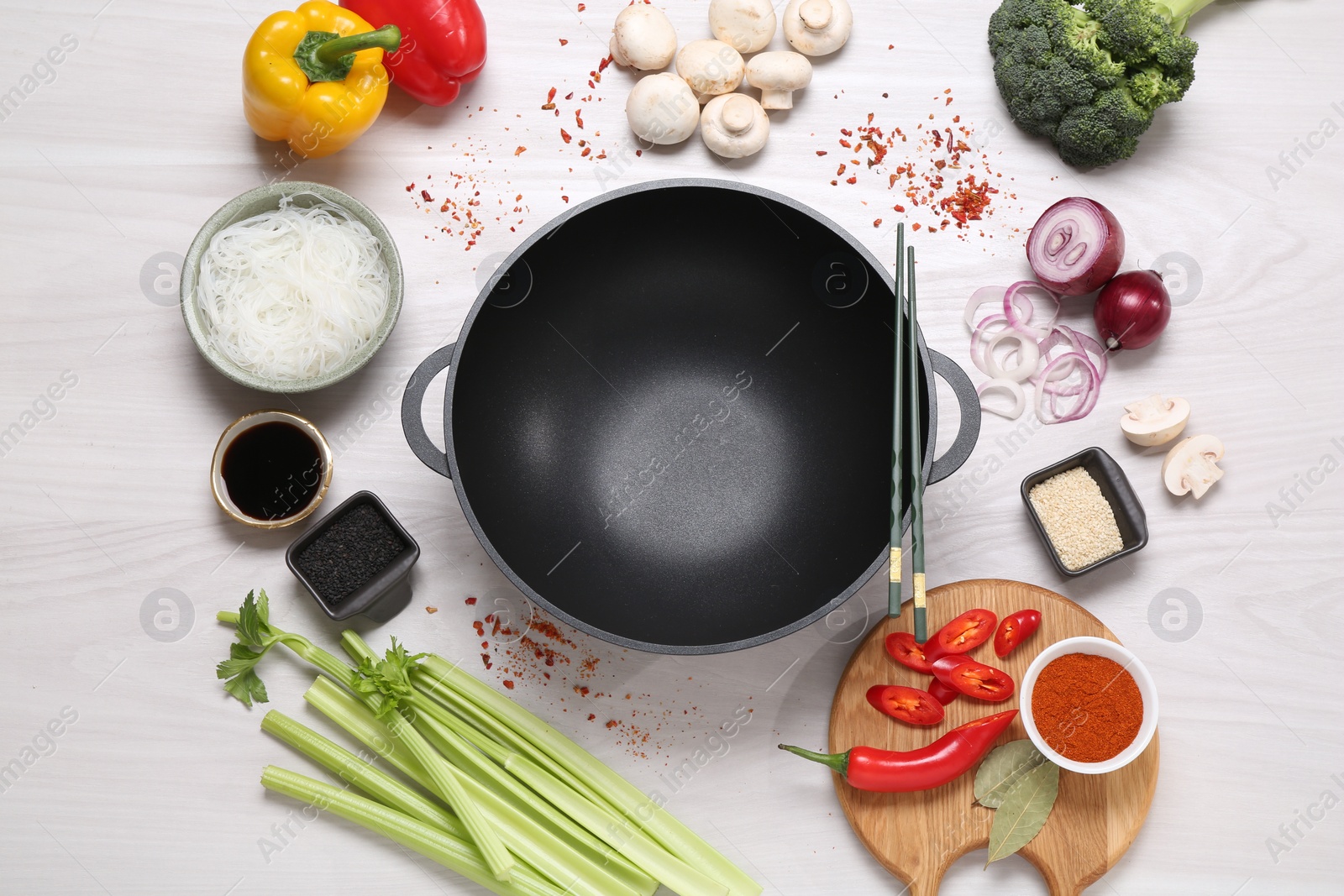 Photo of Wok, chopsticks and different products on white wooden table, flat lay