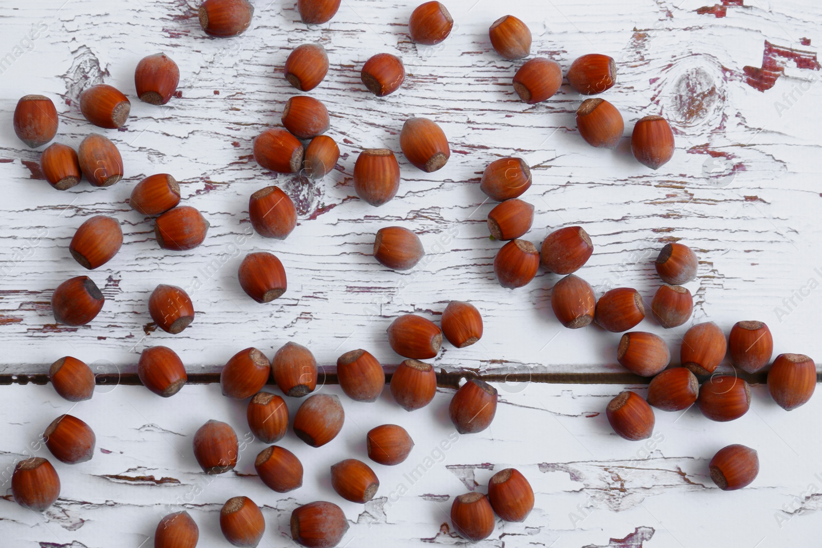 Photo of Tasty hazelnuts on white wooden table, flat lay