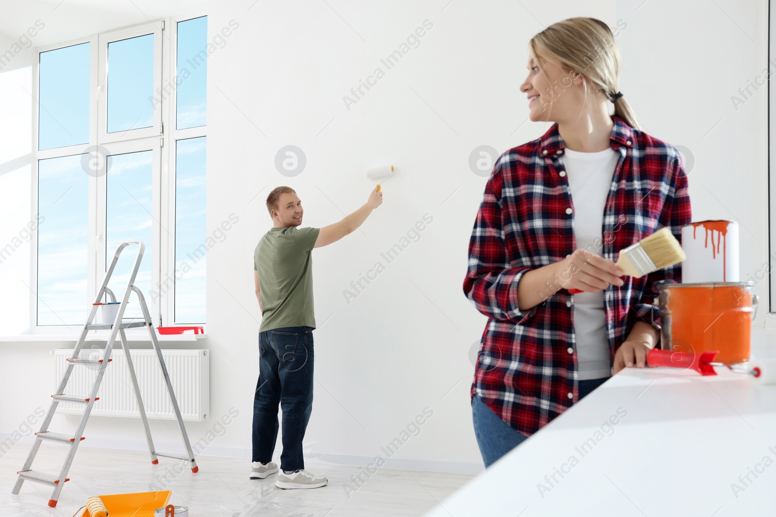 Photo of Couple painting wall in apartment during repair