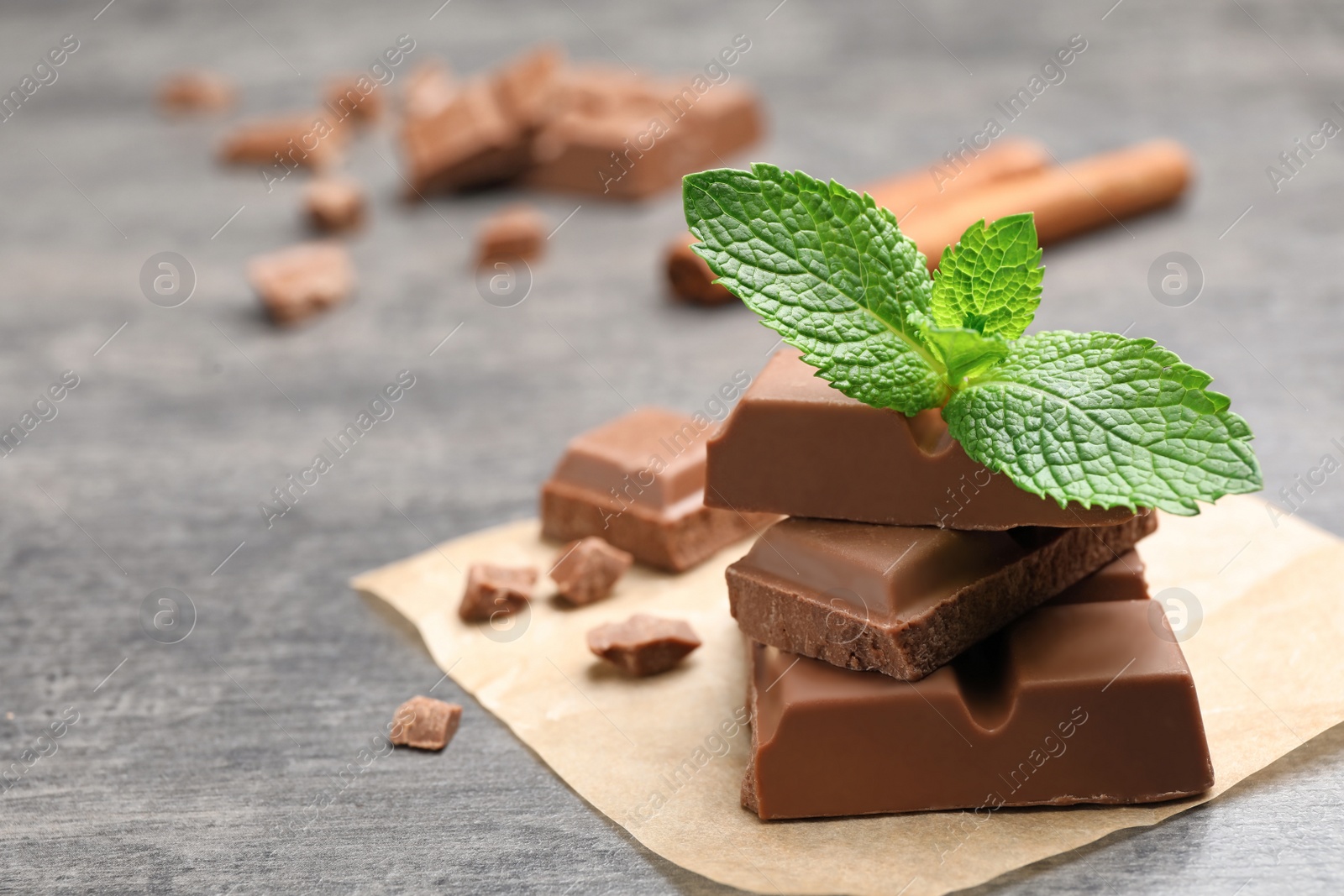 Photo of Pieces of milk chocolate with mint on gray table