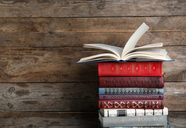 Photo of Stack of hardcover books on wooden background. Space for text