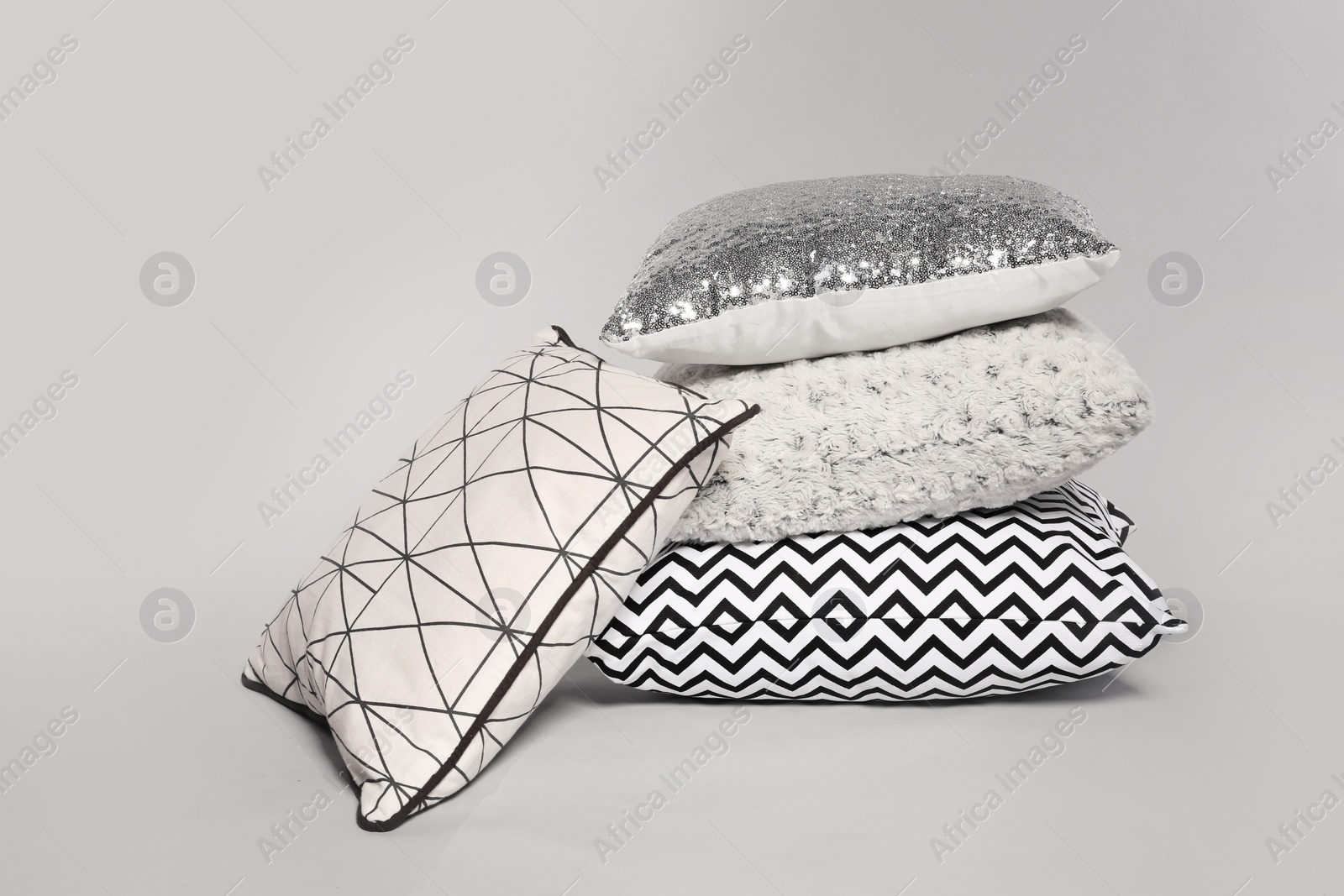 Photo of Stylish decorative pillows stacked on light background