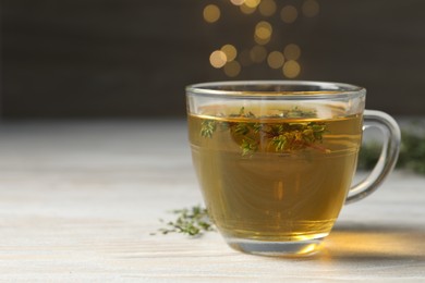 Photo of Cup of fresh thyme tea on wooden table, closeup. Space for text