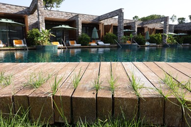 Photo of Wooden deck with grass, swimming pool and recreational area at luxury resort