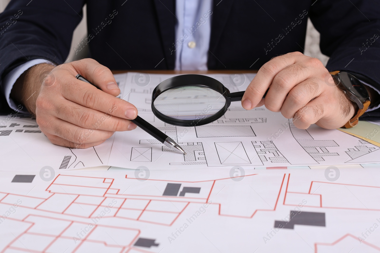 Photo of Professional cartographer working with cadastral map at table, closeup