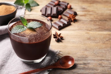 Glass of delicious hot chocolate with fresh mint on wooden table