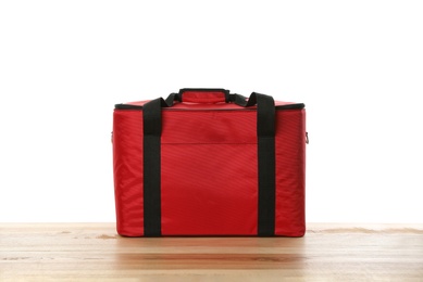 Modern red thermo bag on wooden table against white background