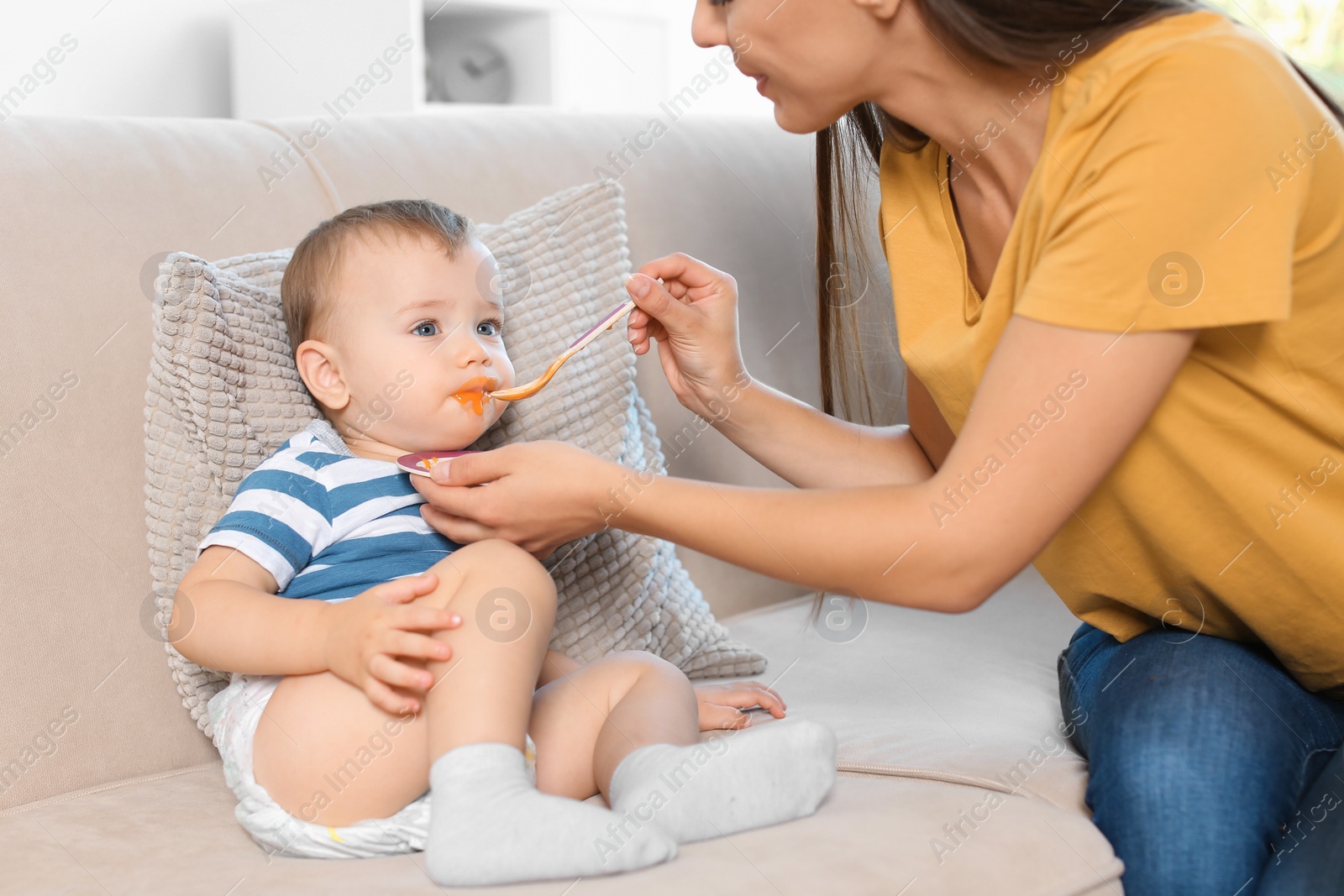 Photo of Woman feeding her child on couch indoors. Healthy baby food