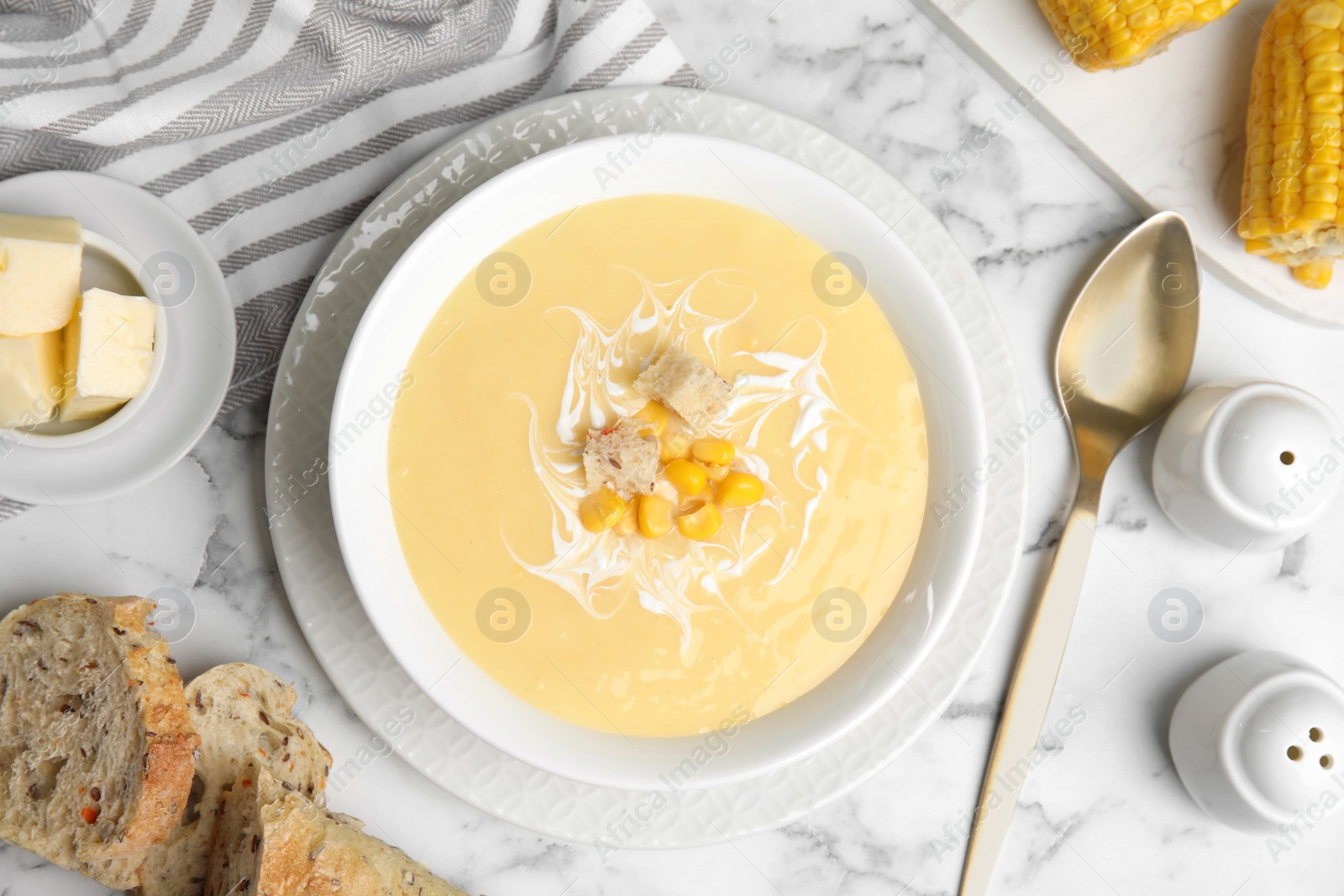 Photo of Delicious corn cream soup served on white marble table, flat lay