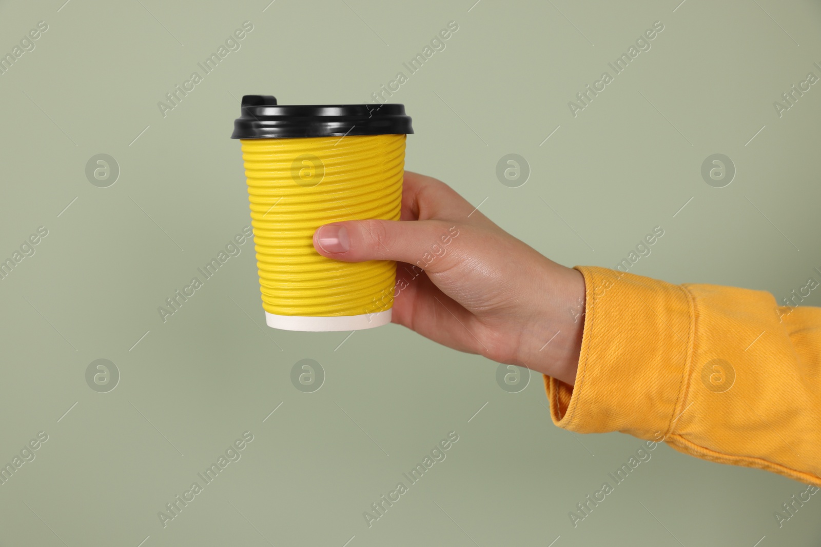 Photo of Woman holding takeaway cup with drink on pale green background, closeup. Coffee to go