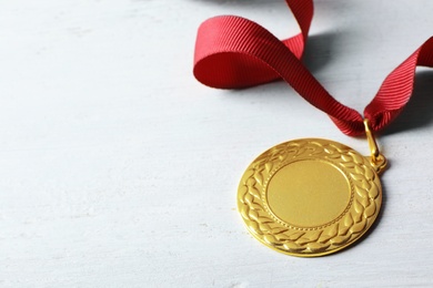 Gold medal with space for design on white wooden background. Victory concept