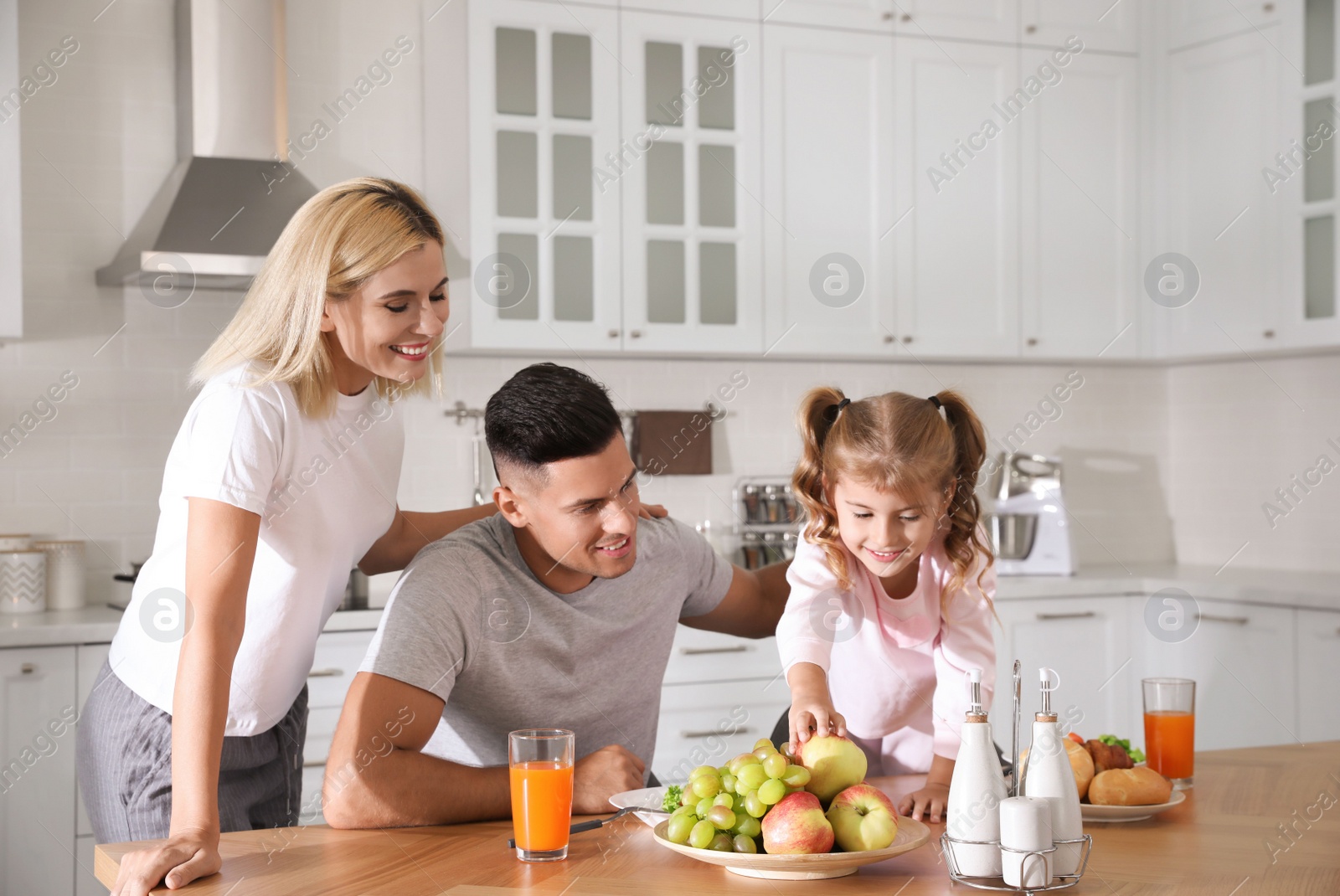 Photo of Happy family having breakfast together at table in modern kitchen