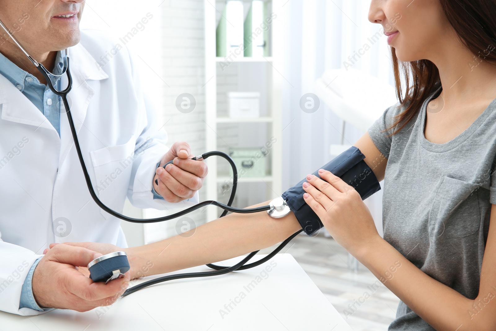 Photo of Young woman visiting doctor in hospital, closeup. Measuring blood pressure and checking pulse