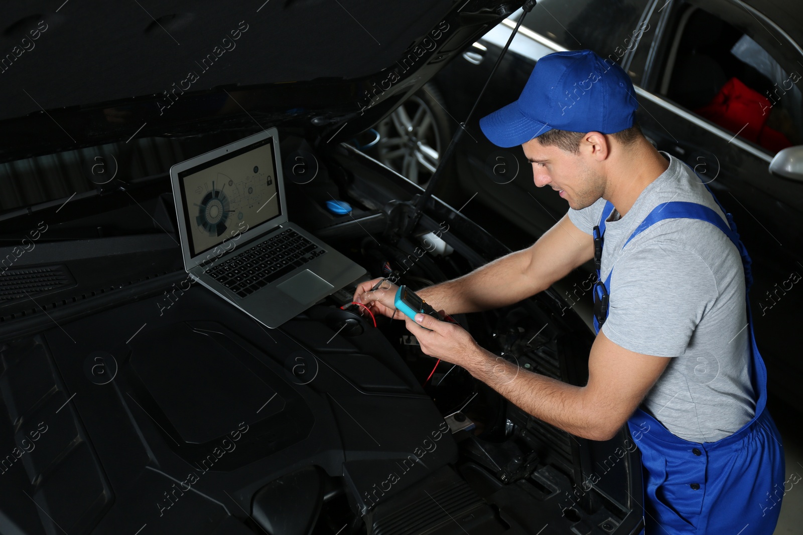 Photo of Mechanic with laptop doing car diagnostic at automobile repair shop