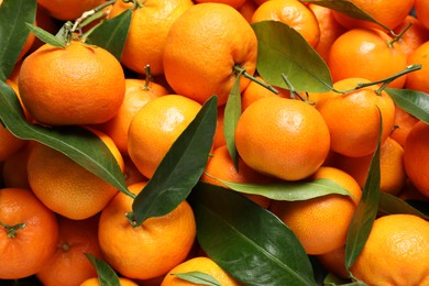 Photo of Fresh ripe tangerines with leaves as background, top view. Citrus fruit