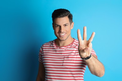 Man showing number three with his hand on light blue background