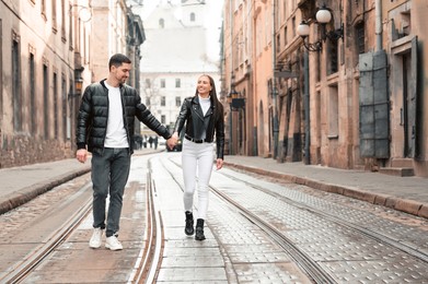 Lovely young couple walking along tram track on pavement road. Romantic date