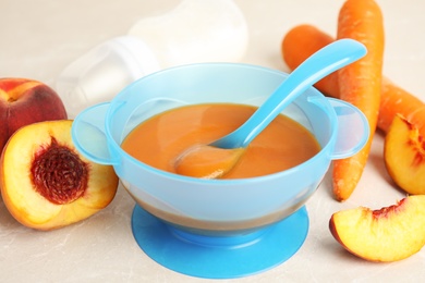 Photo of Baby food in bowl and fresh ingredients on light grey table