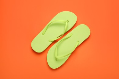 Stylish light green flip flops on orange background, top view