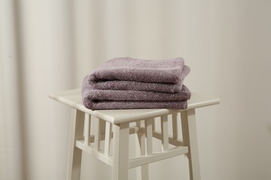 Violet towels on stool against white wall