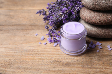Photo of Stones, jar of cream and lavender flowers on wooden table. Space for text