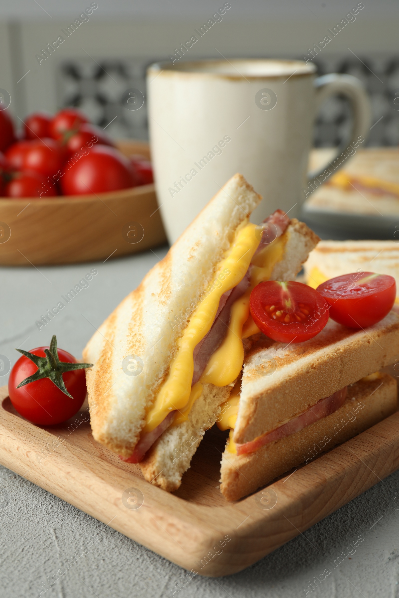 Photo of Tasty sandwiches with ham, melted cheese and tomatoes on grey textured table, closeup