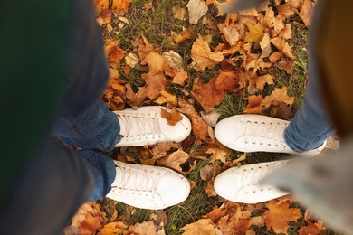 Couple standing on ground covered with leaves in park, above view. Autumn walk