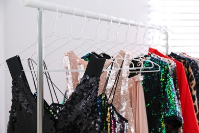 Stylish party dresses on rack indoors, closeup