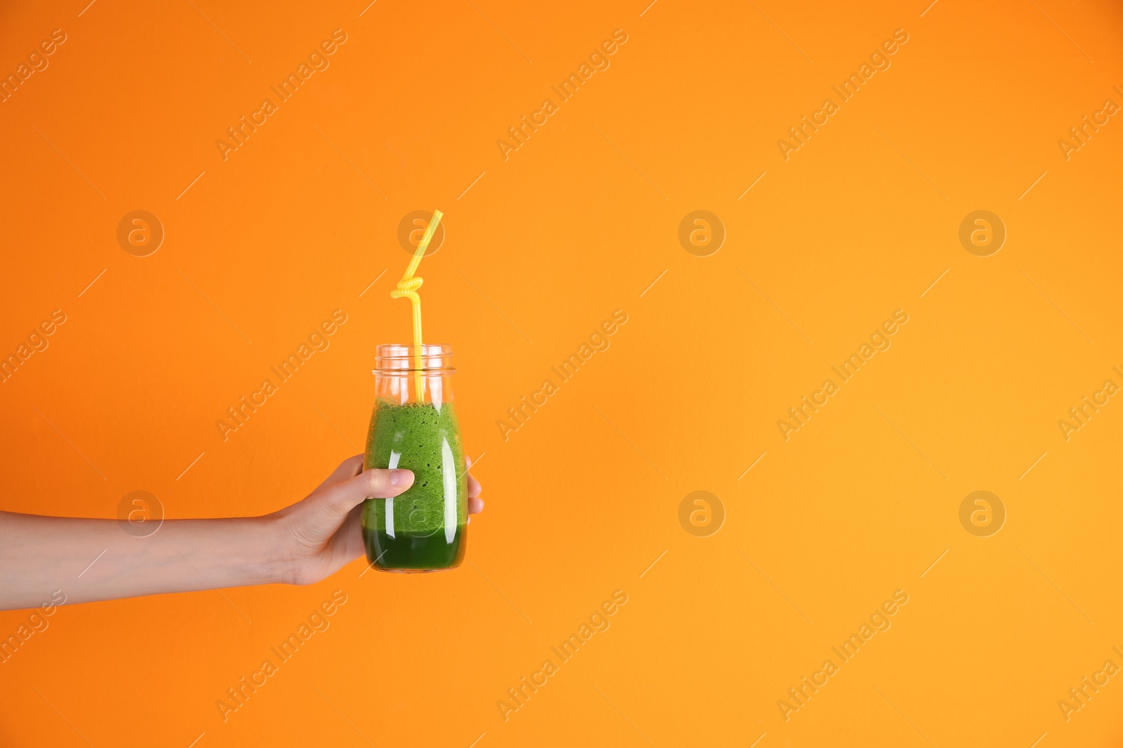 Photo of Young woman holding bottle of healthy smoothie on color background