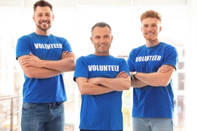 Portrait of happy male volunteers in uniform indoors