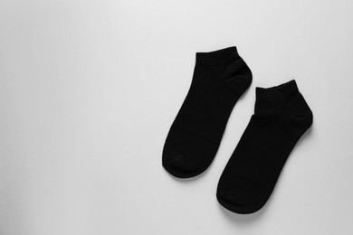 Pair of black socks on light grey background, flat lay. Space for text