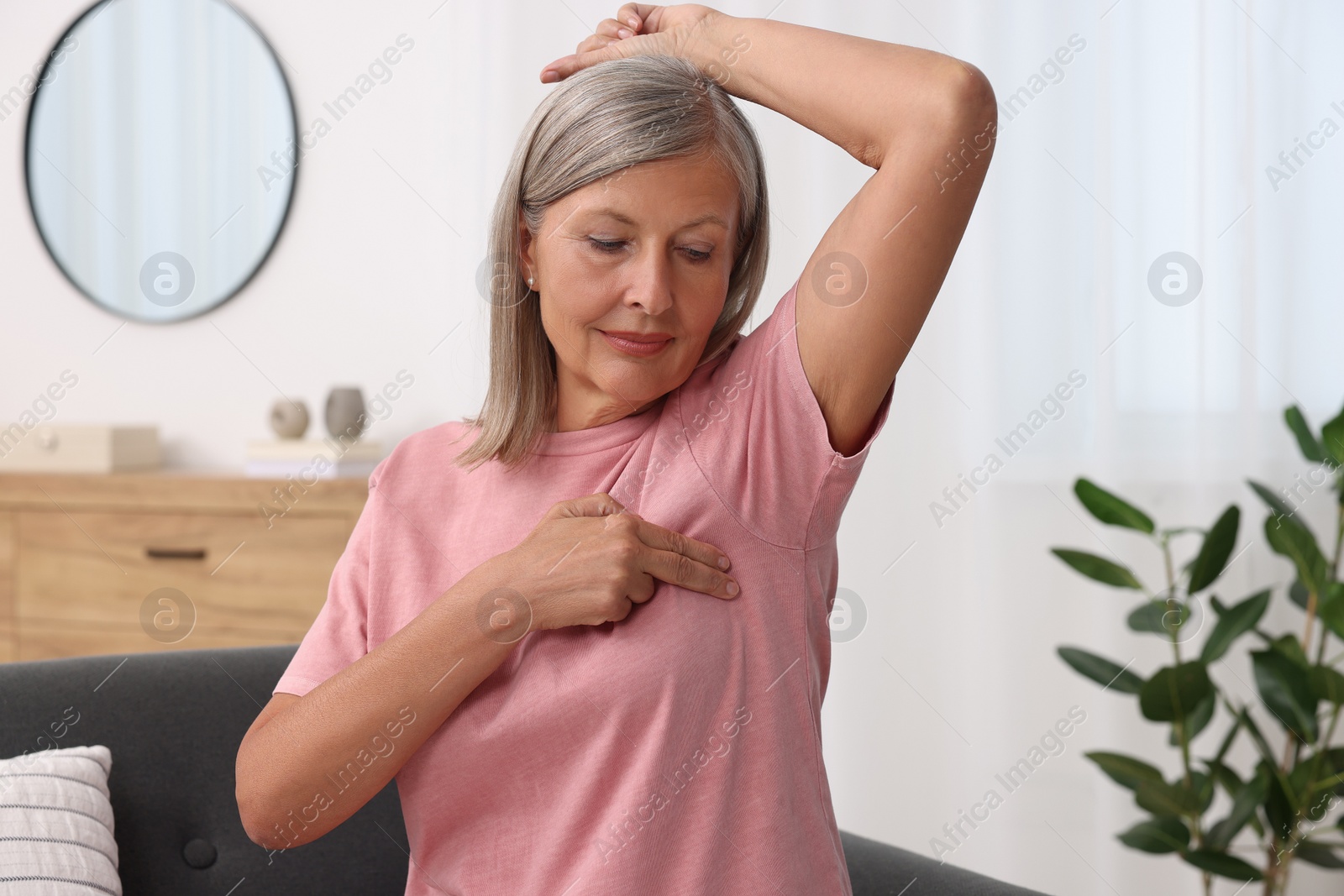 Photo of Beautiful senior woman doing breast self-examination at home