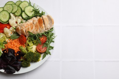 Balanced diet and healthy foods. Plate with different delicious products on white tiled table, top view. Space for text