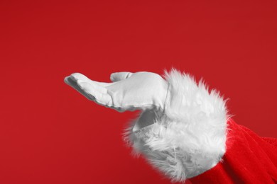 Photo of Merry Christmas. Santa Claus holding something on red background, closeup